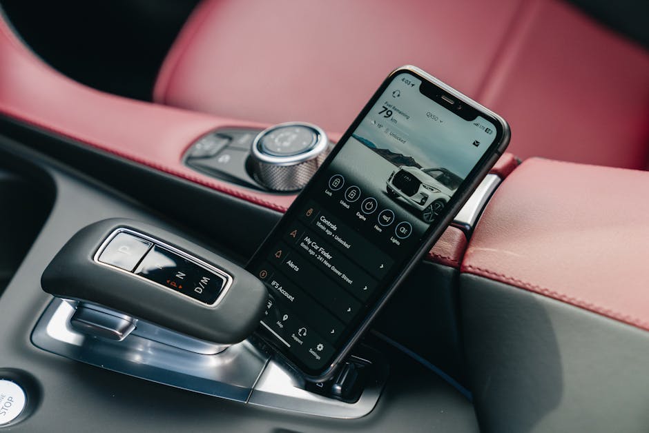 Pametni telefon s aplikacijom za upravljanje vozilom u interijeru luksuznog automobila